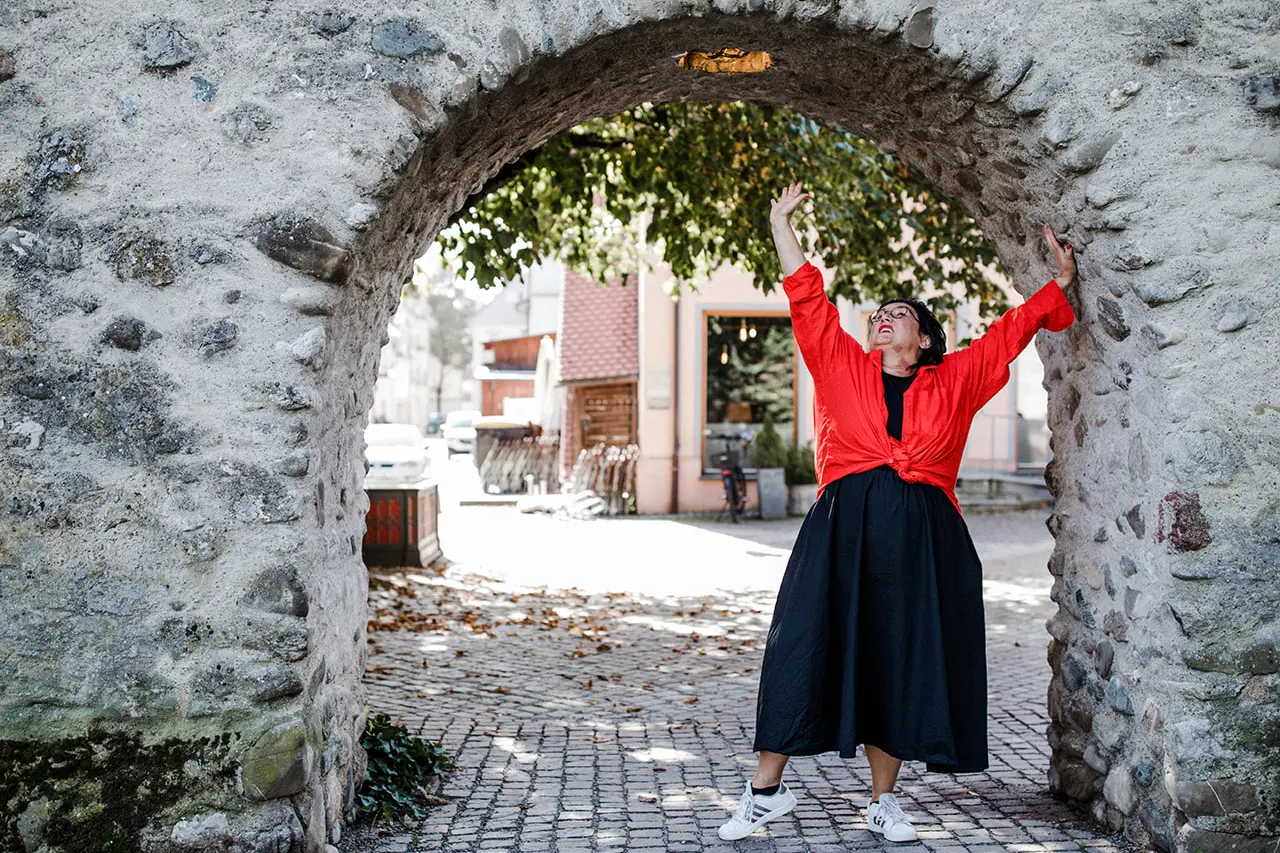 Frau in roter Jacke unter Steinbogen